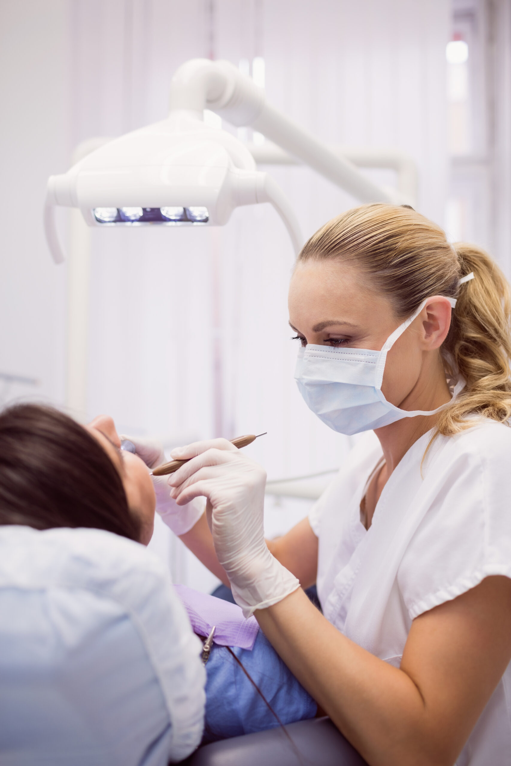 Dentist examining female patient in clinic