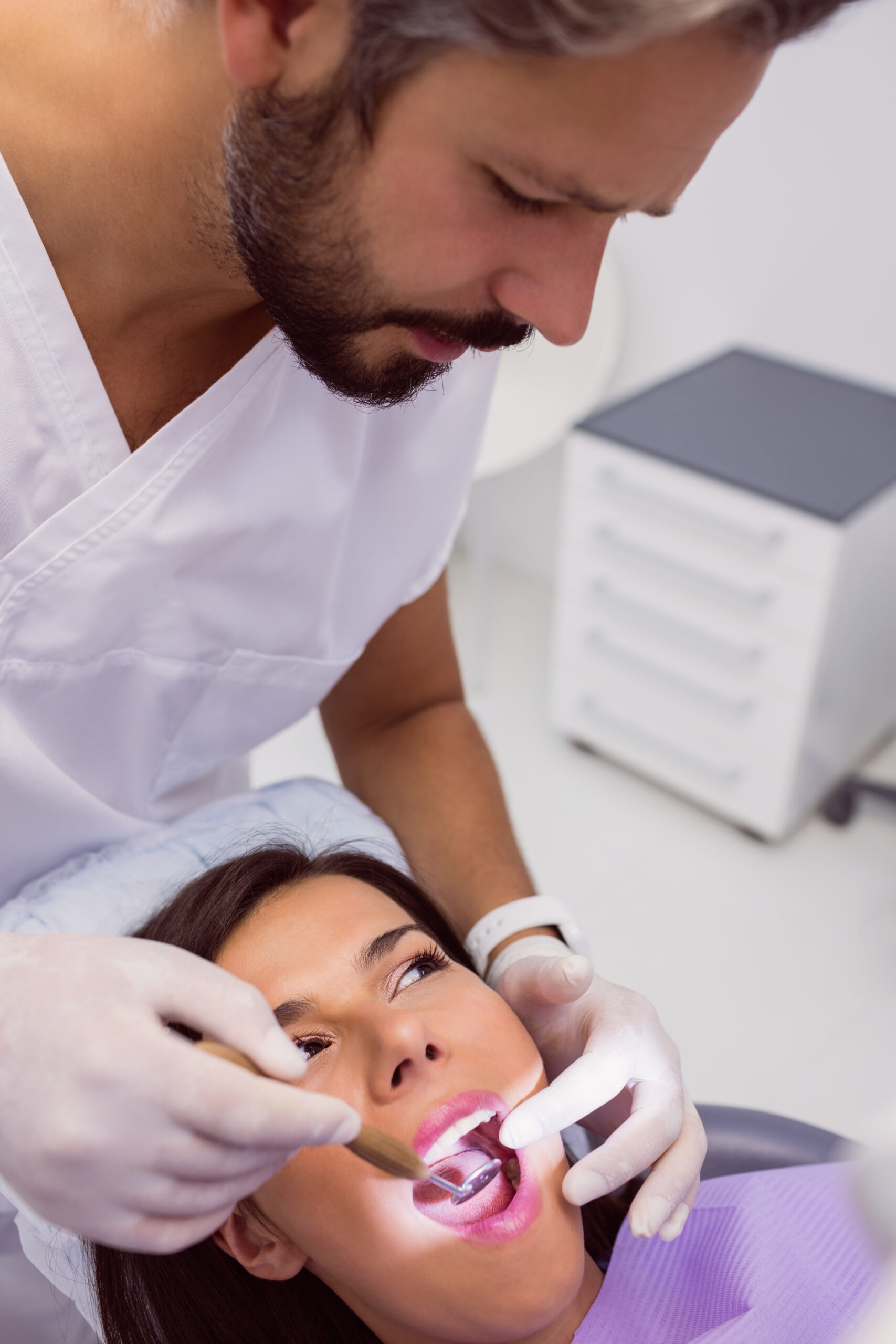 Dentist examining female patient teeth with a mouth mirror in clinic