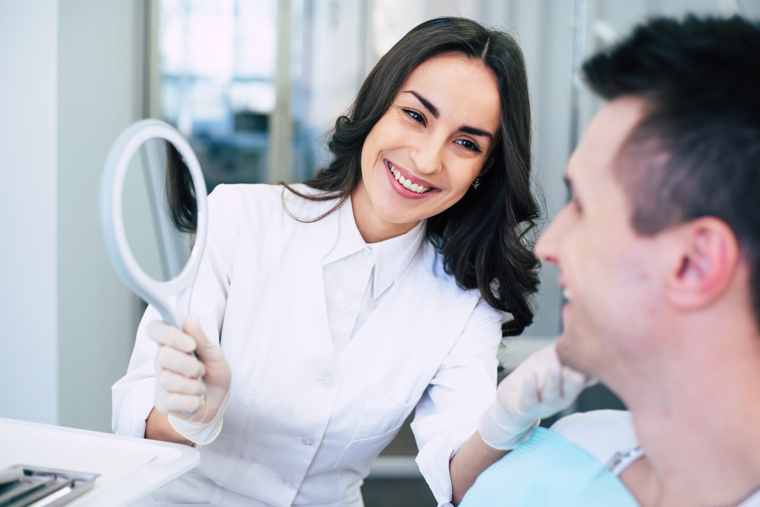 Smiling woman who is working as a dentist smiles sincerely because of the result which she has done for her patient